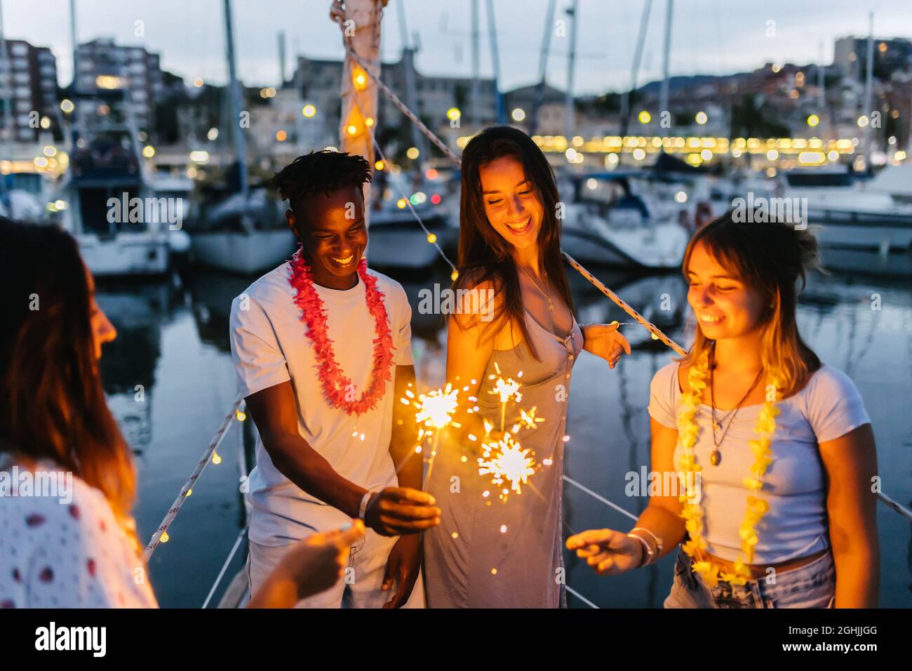 Glückliche Menschen feiern gemeinsam Geburtstag oder heiligabend mit Wunderkerzen auf dem Boot Stockfoto