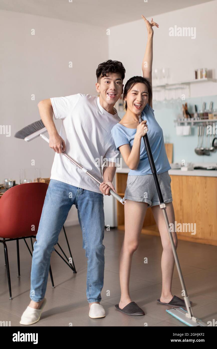 Fröhliches junges Paar, das Hausarbeit leistet Stockfoto