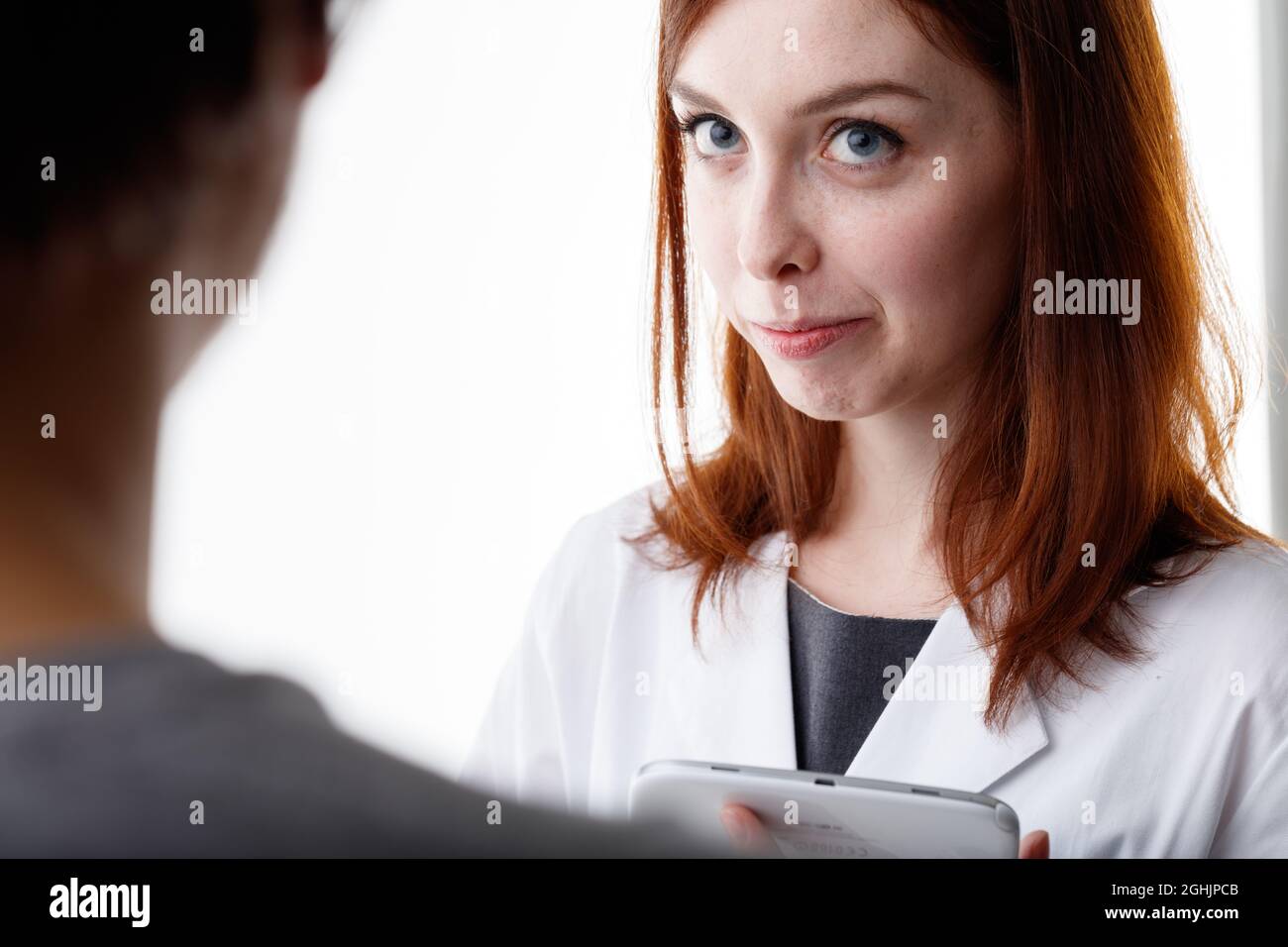 Frau, die einer Freundin oder Arbeitskollegin aufmerksam zuhört, in einer über die Schulter zugeschnittenen Ansicht ihres Gesichts mit weiten Augen und einem ernsthaften nachdenklichen Exp Stockfoto