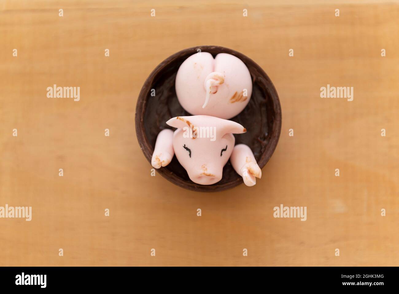 Draufsicht auf verzierte Süßigkeiten, fröhliche süße rosa Schweine, die im Schlamm aus Marzipan und Schokolade spielen. Selektiver Fokus. Kleine Schweine haben Spaß in der mu Stockfoto
