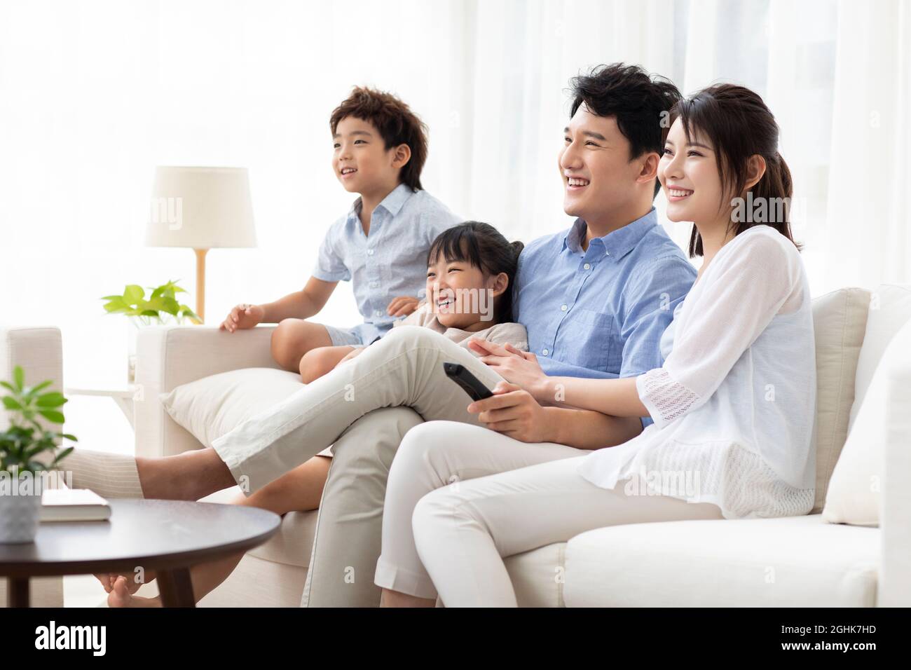Glückliche junge Familie, die zu Hause Fernsehen schaut Stockfoto