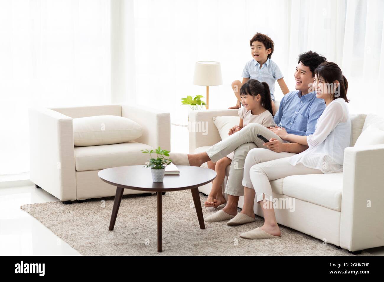 Glückliche junge Familie, die zu Hause Fernsehen schaut Stockfoto