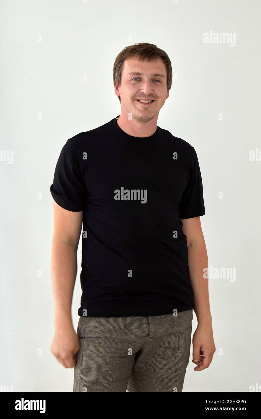 Junges männliches Modell mit einfachem schwarzen T-Shirt mit Platz für Aufdruck vor weißem Hintergrund Stockfoto