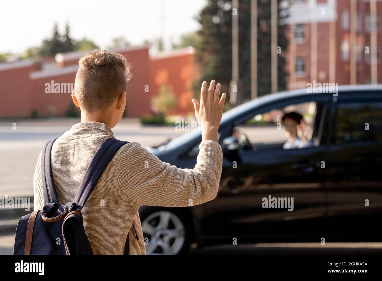 Der Schuljunge sagte Auf Wiedersehen zu seiner Mutter im Auto, bevor er morgens zur Schule ging Stockfoto