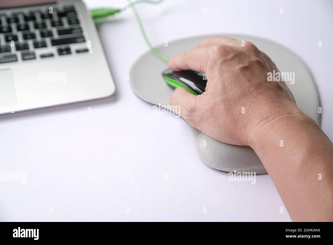 Die Hand des Mannes klickt auf die Maus, ruht sein Handgelenk auf der Handgelenkstütze oder unterstützt Memory Foam. Nahaufnahme. Stockfoto