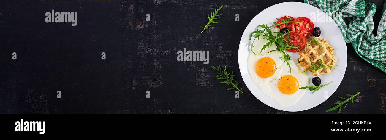 Frühstück mit Zucchini-Waffeln, Spiegeleiern, Tomaten, schwarzen Oliven und Rucola auf weißem Hintergrund. Vorspeisen, Snacks, Brunch. Gesundes vegetarisches Essen. Stockfoto