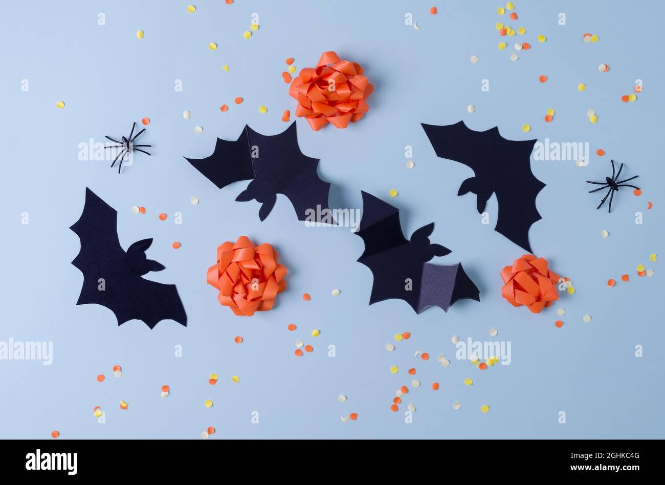 Dekorative Fledermäuse, Spinnen, orangefarbene Schleifen auf blauem Hintergrund mit Süßigkeiten. Happy Halloween Urlaub Hintergrundkonzept, flaches Layout Stockfoto