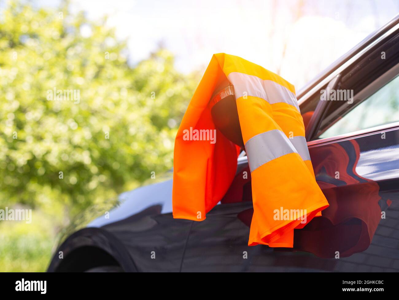 Eine orangefarbene Warnweste hängt am Spiegel eines Pkw