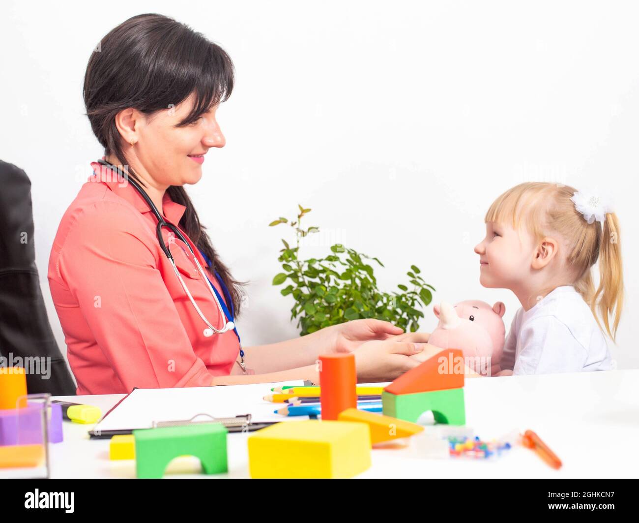 Eine kaukasische Frau, ein Kinderarzt, eine Psychotherapeutin, nimmt Kontakt mit einer Patientin, einem Kind im Alter von 3-4 Jahren, auf. Stockfoto