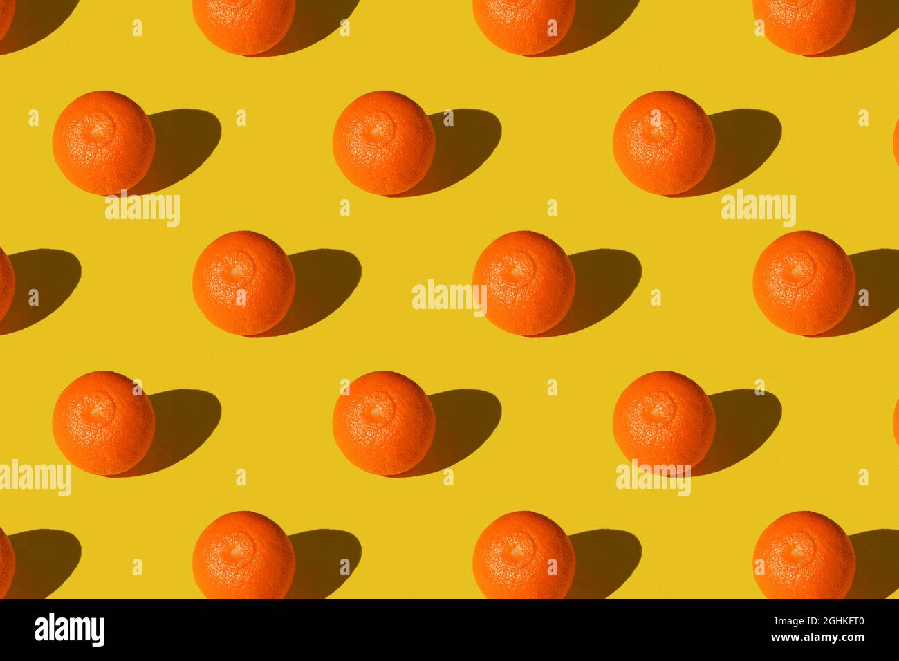 Trendiger Sommer Nahtloses Muster aus saftiger oranger Manadarin-Mandarine mit Schatten auf sonnengelbem Hintergrund. Minimaler Sommerurlaub Konzept. Gesunde Foo Stockfoto