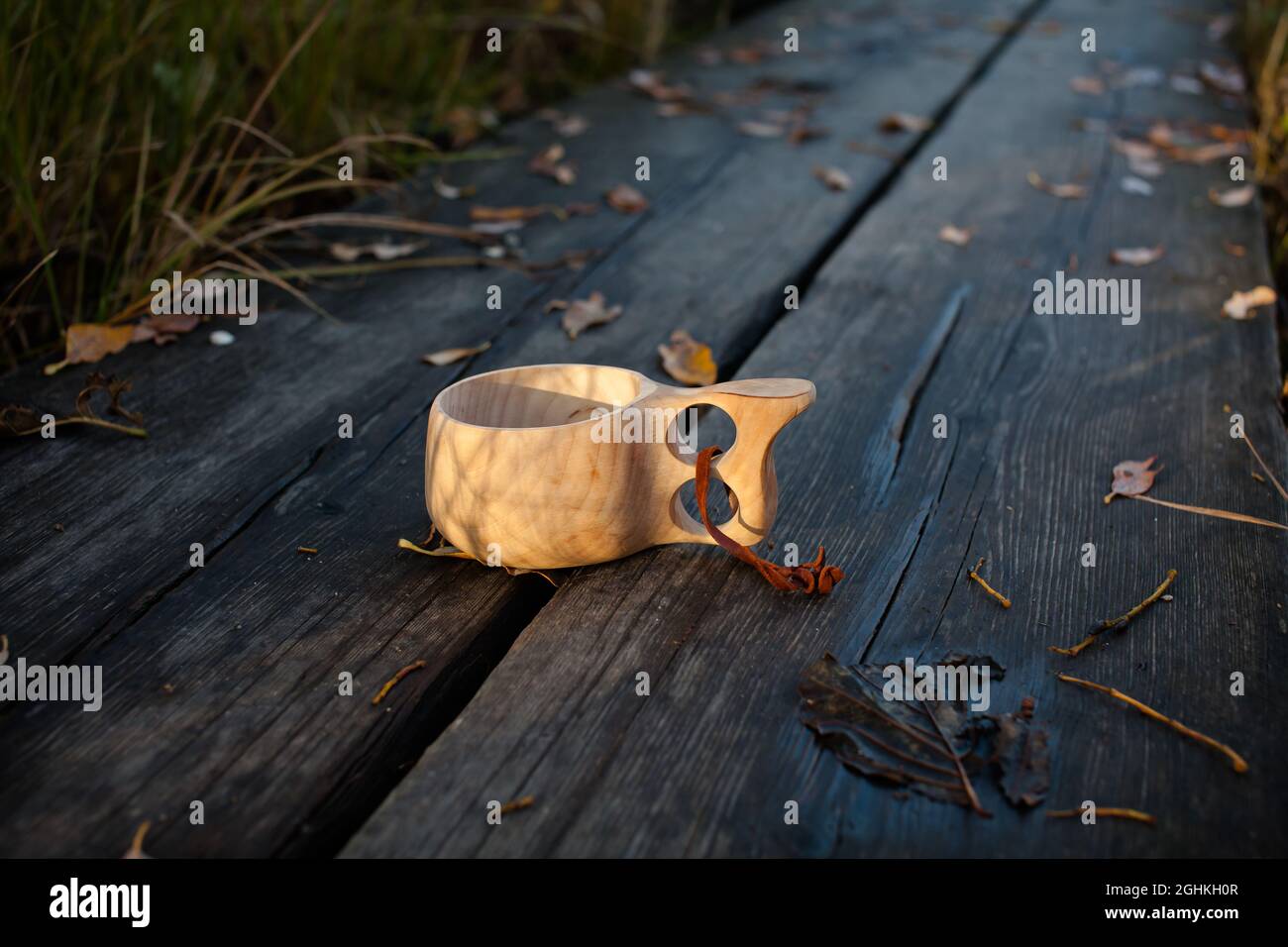 Nahaufnahme eines leeren Holzbechers auf Drückwänden im Herbst, mit heruntergefallenen Blättern im Hintergrund. Stockfoto