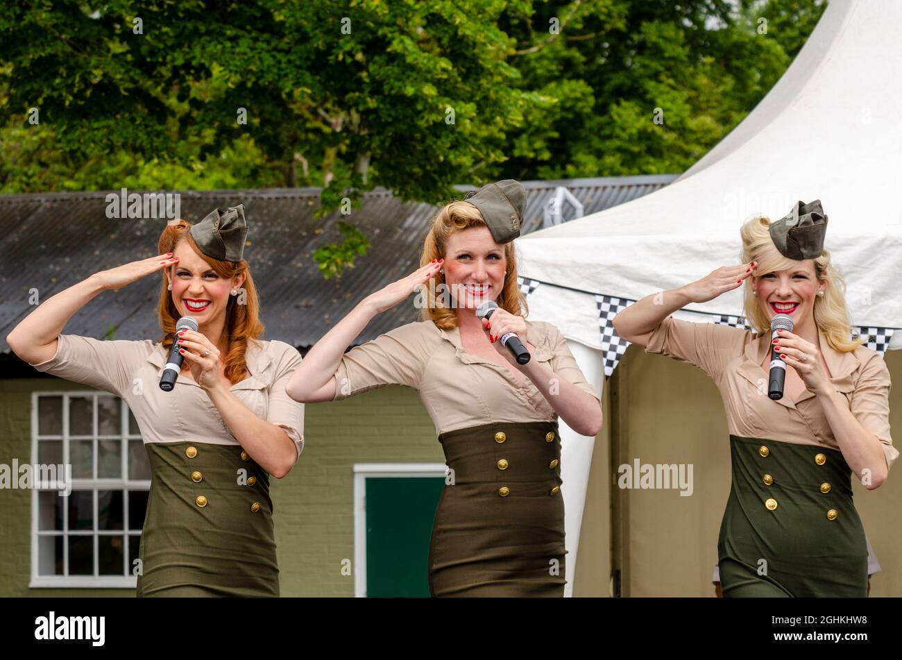 Manhattan Dolls singen in England bei einer militärischen Wiederbelebung Veranstaltung. Sängerinnen aus Amerika besuchen Großbritannien, tragen Uniformen im USAAF-Stil und grüßend Stockfoto