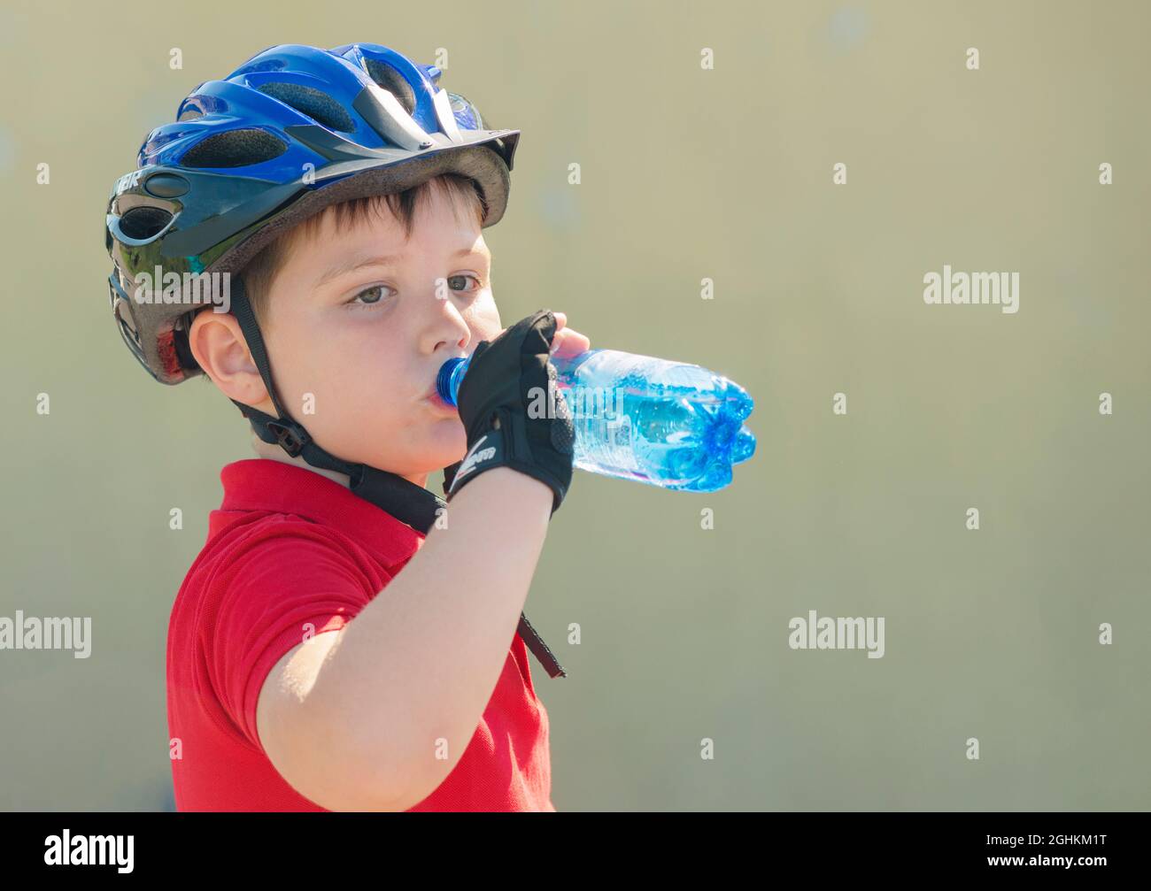 Junge auf Fahrrad und Trinkwasser aus Plastikflasche Stockfoto