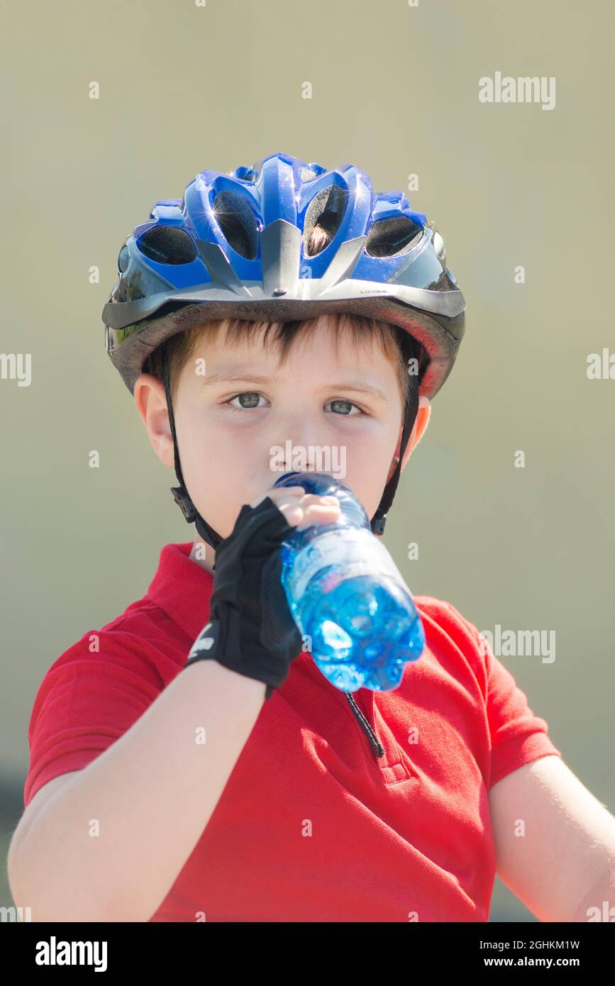 Junge auf Fahrrad und Trinkwasser aus Plastikflasche Stockfoto