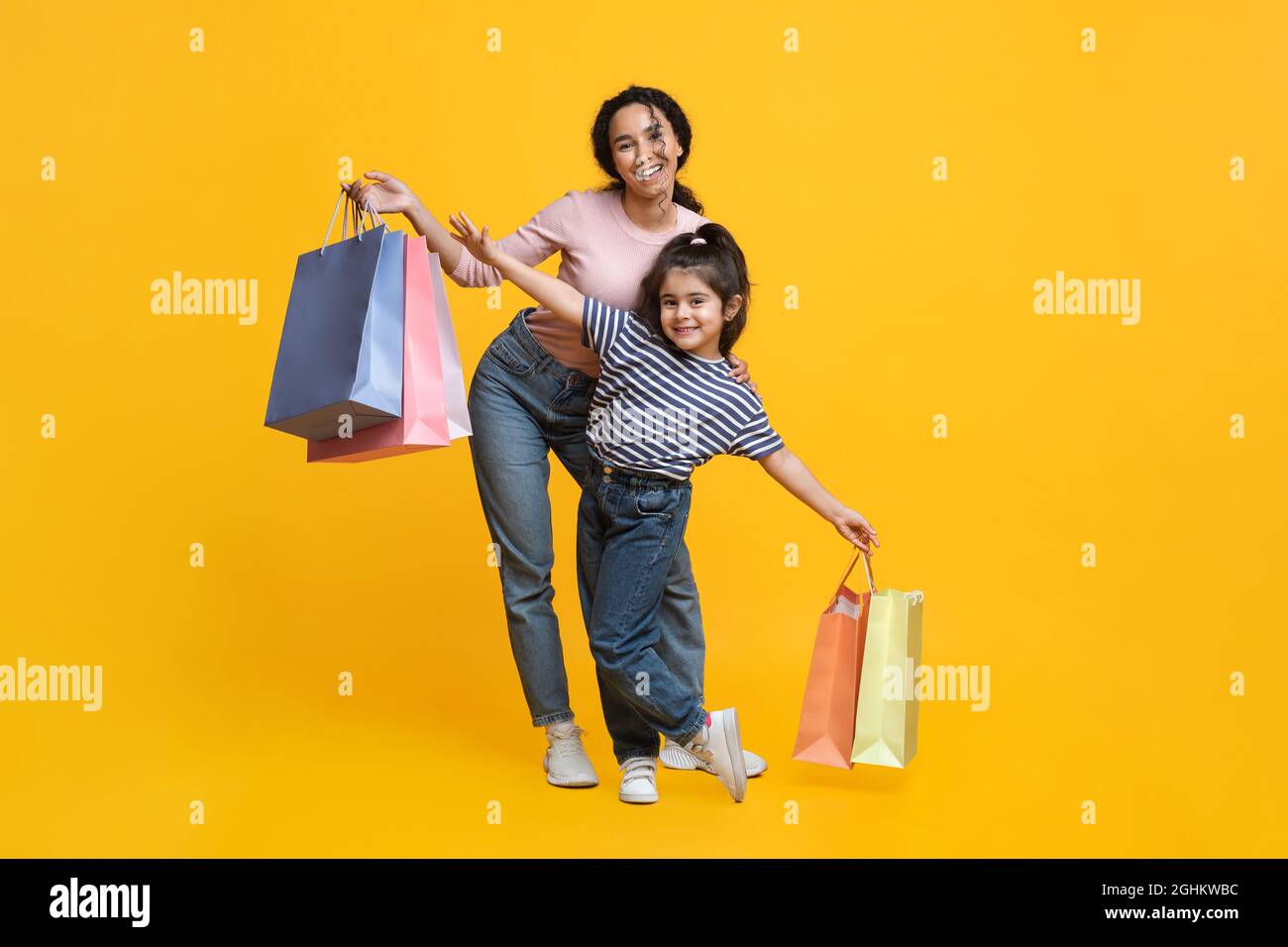 Einkaufen Mit Mama. Happy Middle-Eastern Mutter Und Kleine Tochter Tragen Shopper Taschen Stockfoto