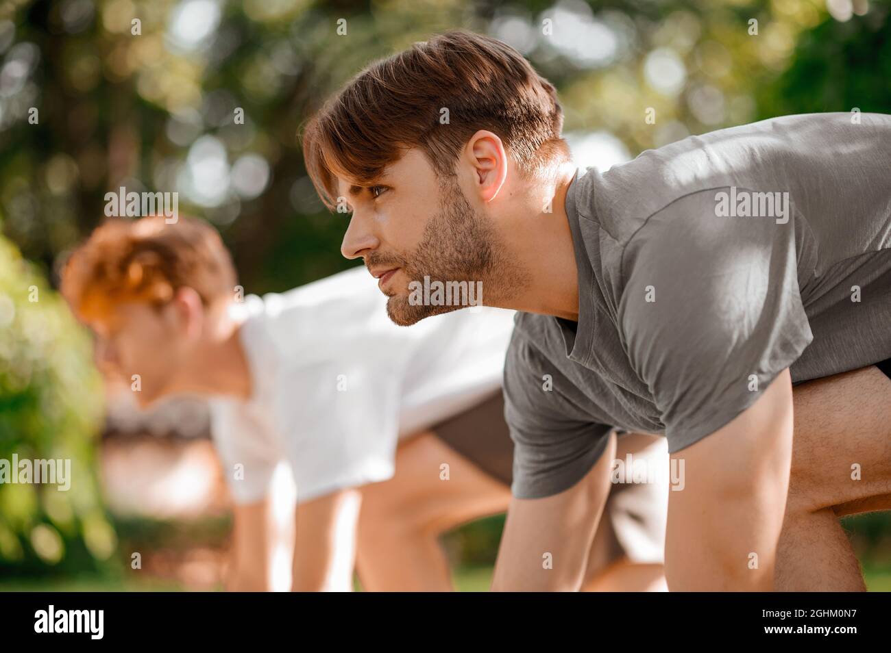 Dunkelhaariger, zielstrebiger Kerl zu Beginn des Laufs und Freund Stockfoto