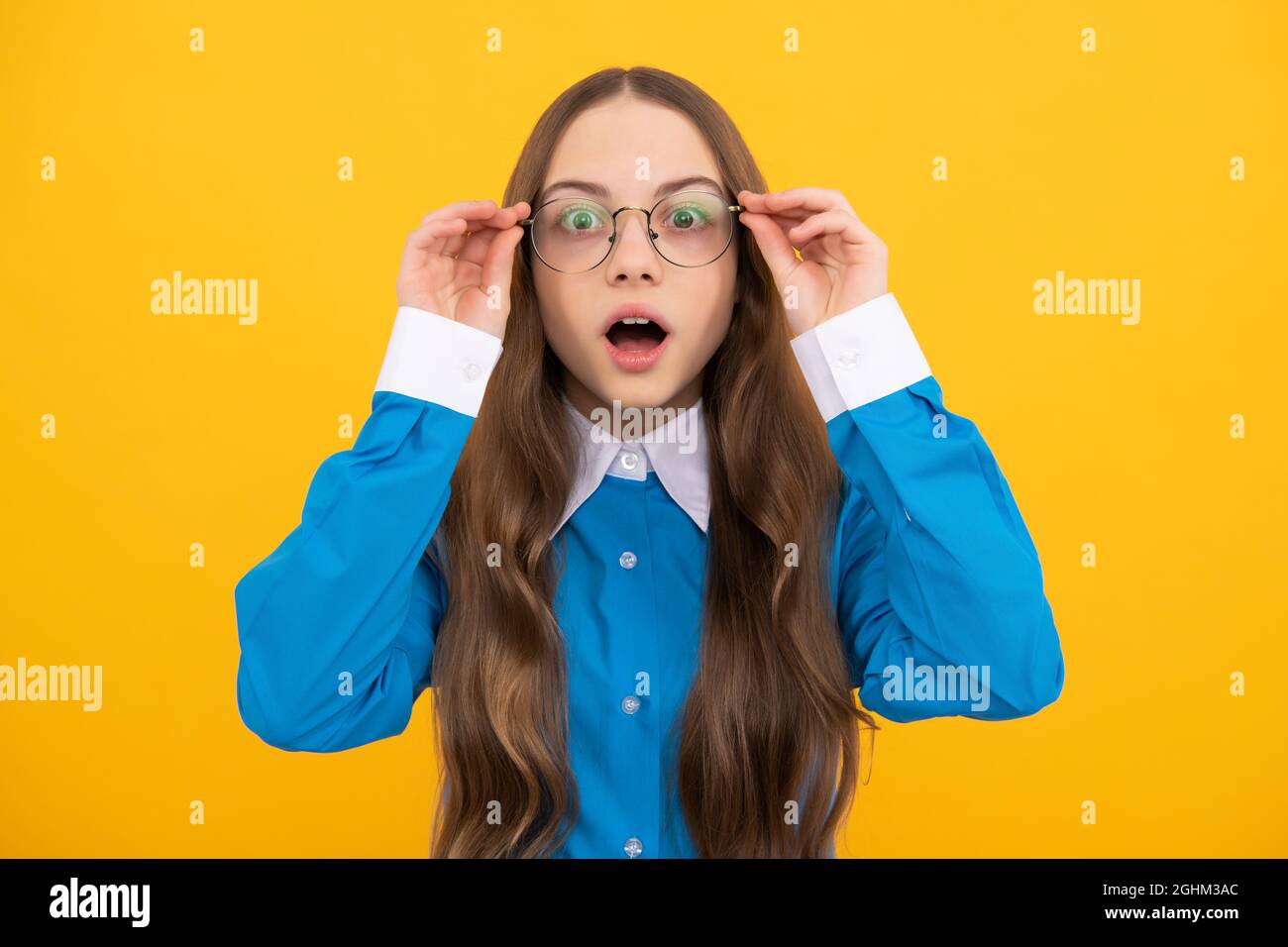 Schockiert Mädchen im Alter von der Schule in einer Brille mit staunenden Blick gelben Hintergrund, Erstaunen Stockfoto