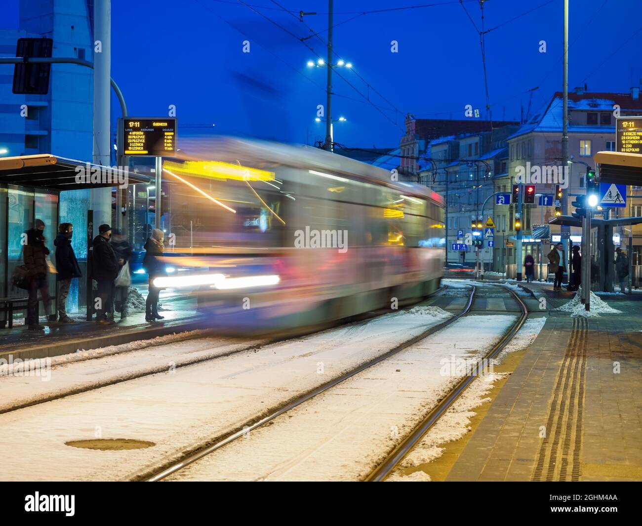 Die Menschen in der Straßenbahn halten an und nähern sich der Straßenbahn in einer Bewegung in der Nacht Stockfoto
