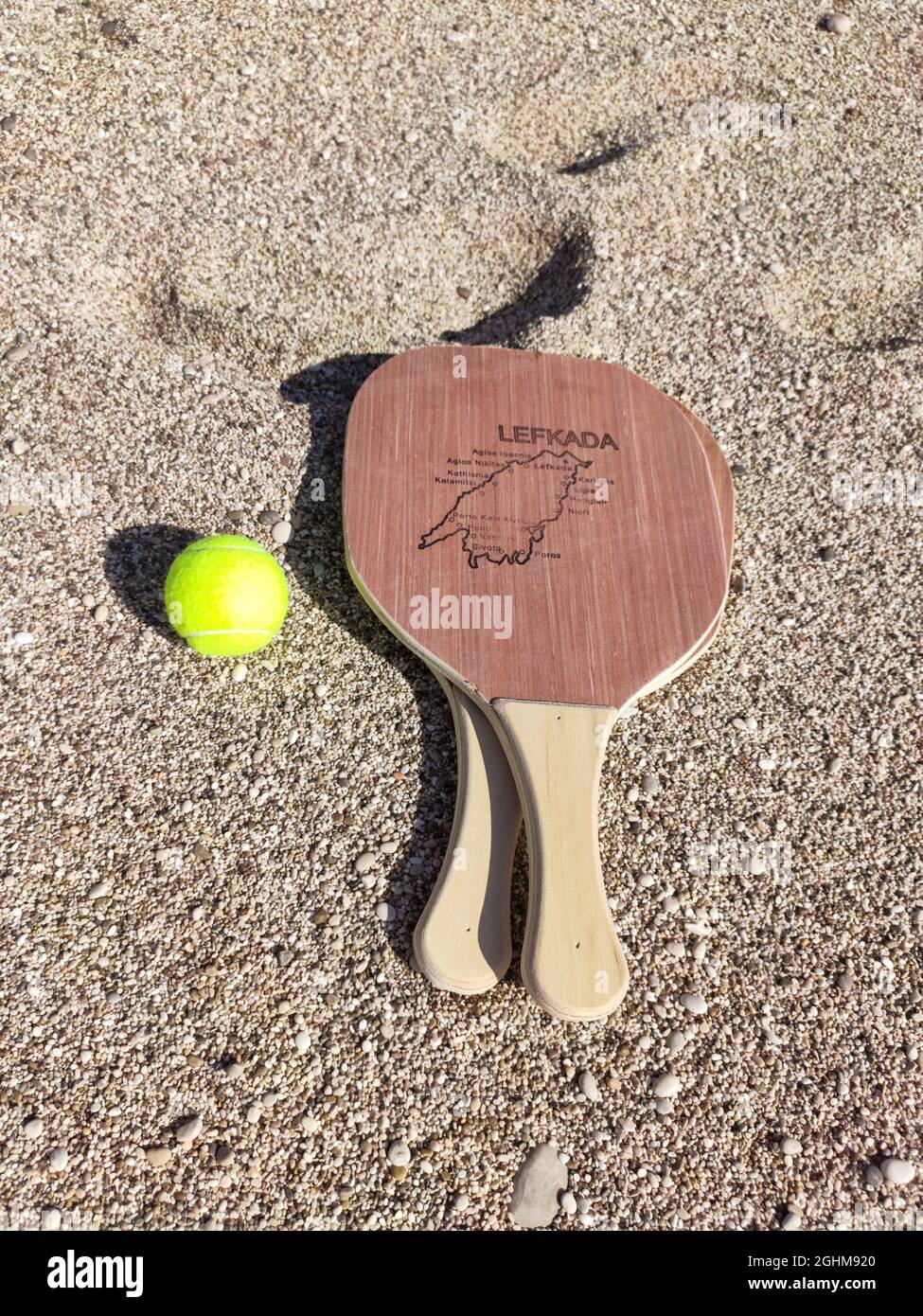 Matkot griechisches Paddle Beach Tennis Spiel mit Ball und Holzschlägern mit Karte der Insel Lefkada, Griechenland. Sportausrüstung am Sandstrand in Griechenland. Verti Stockfoto