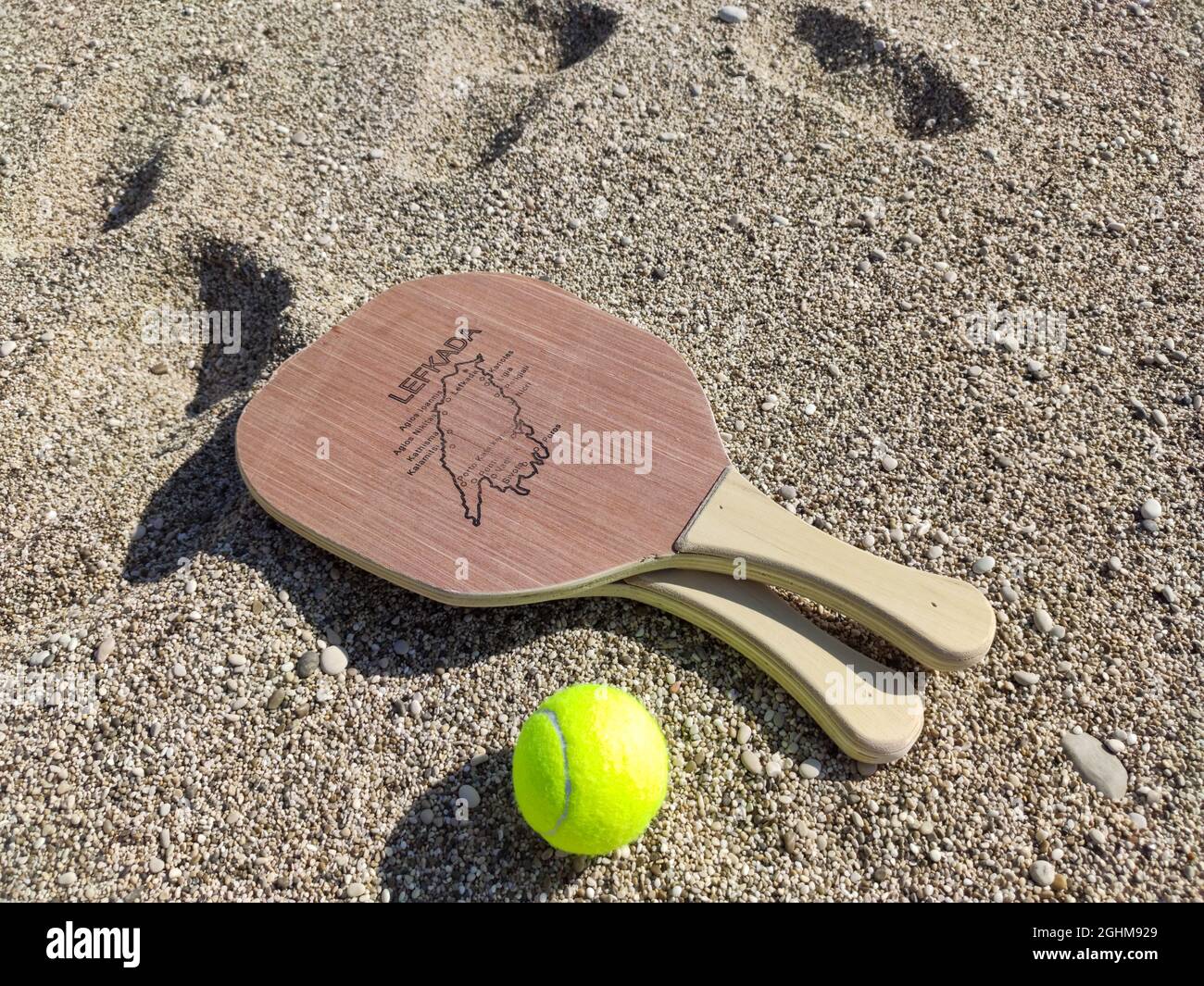 Matkot griechisches Paddle Beach Tennis Spiel mit Ball und Holzschlägern mit Karte der Insel Lefkada. Sportausrüstung am Sandstrand in Griechenland Stockfoto
