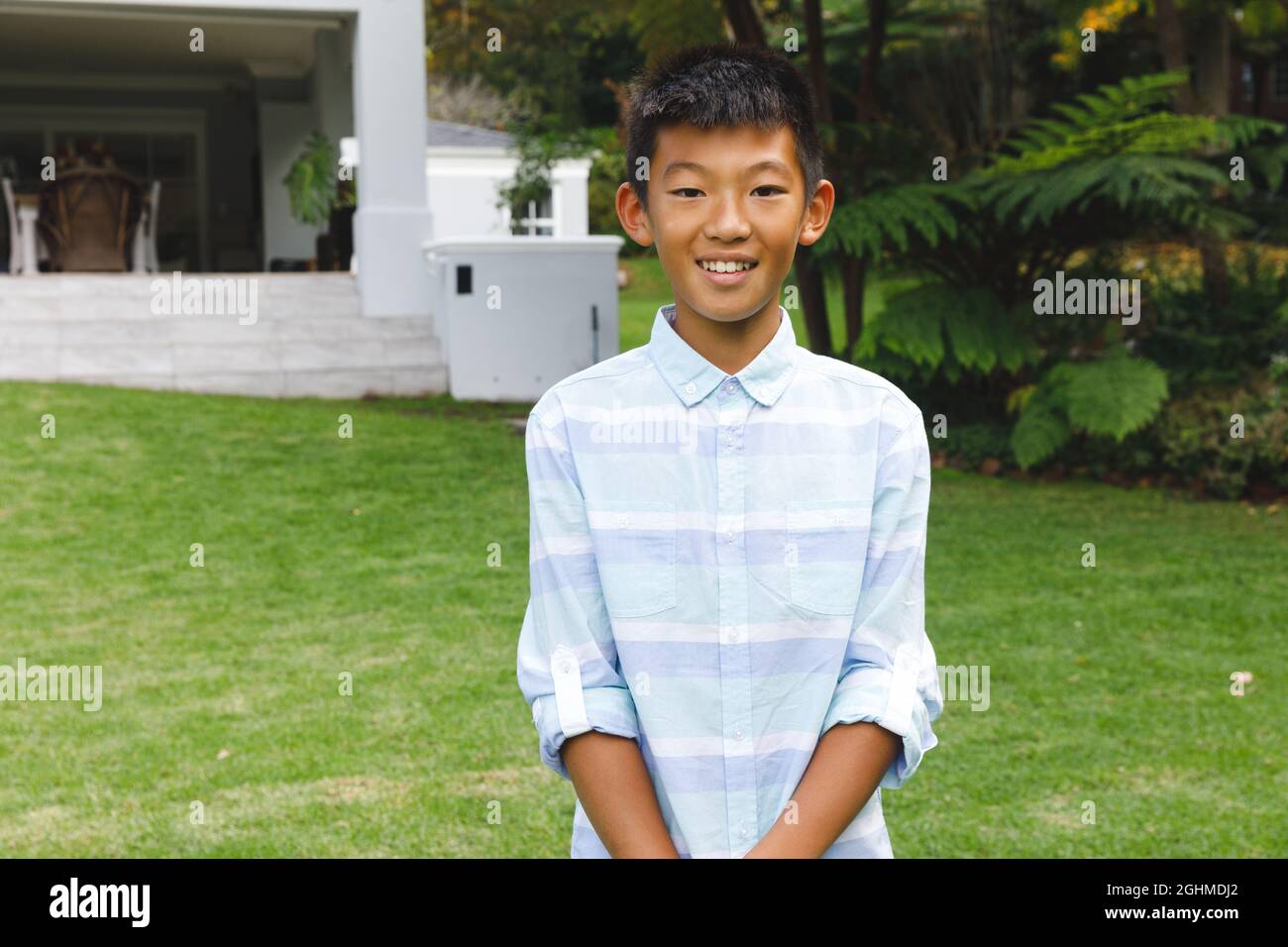 Porträt eines lächelnden asiatischen Jungen, der im Freien lächelt und im Garten legere Kleidung trägt Stockfoto
