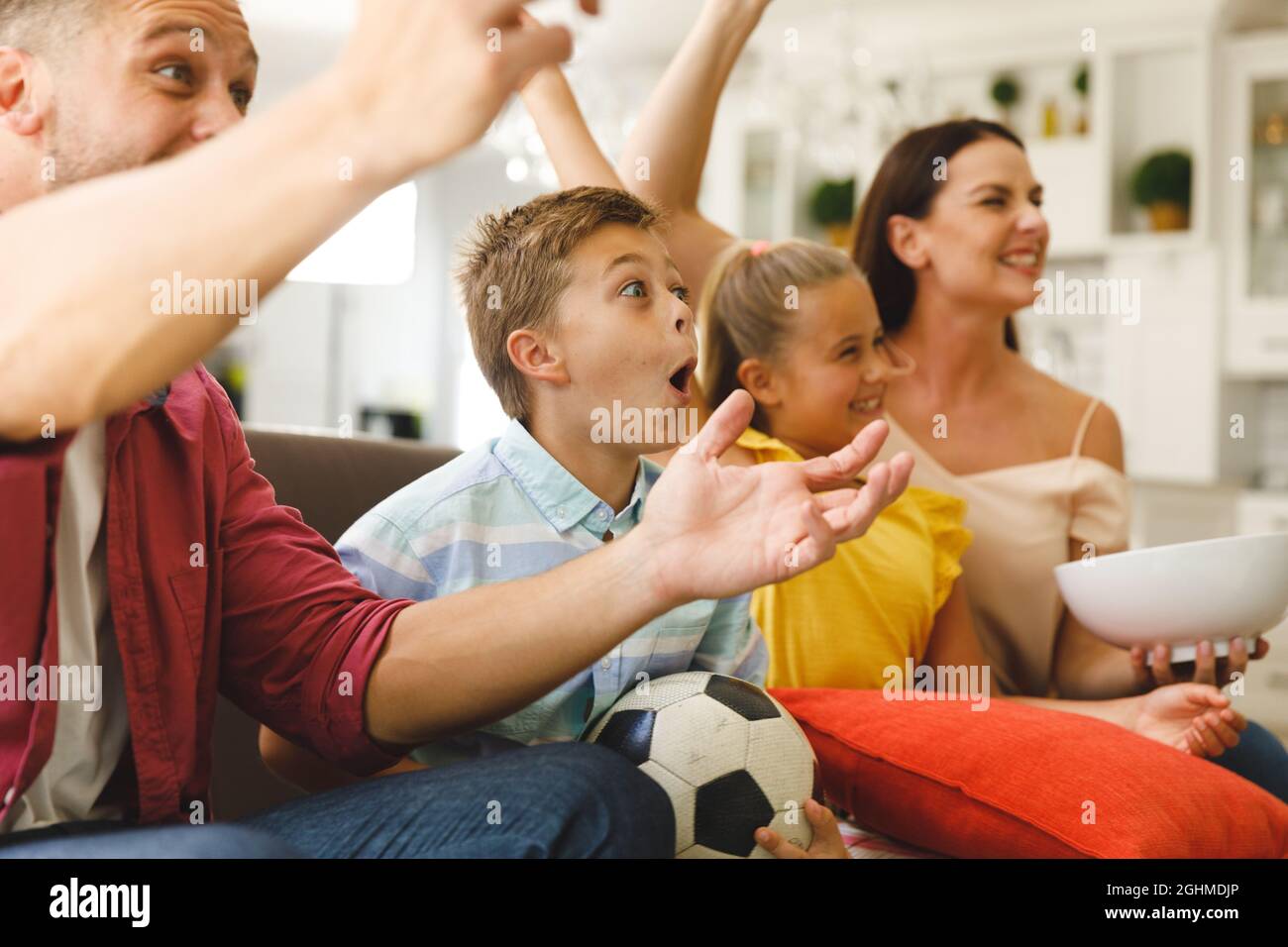 Aufgeregte kaukasische Eltern auf der Couch mit Tochter und Sohn, die sich ein Fußballspiel im fernsehen ansahen und jubelten Stockfoto