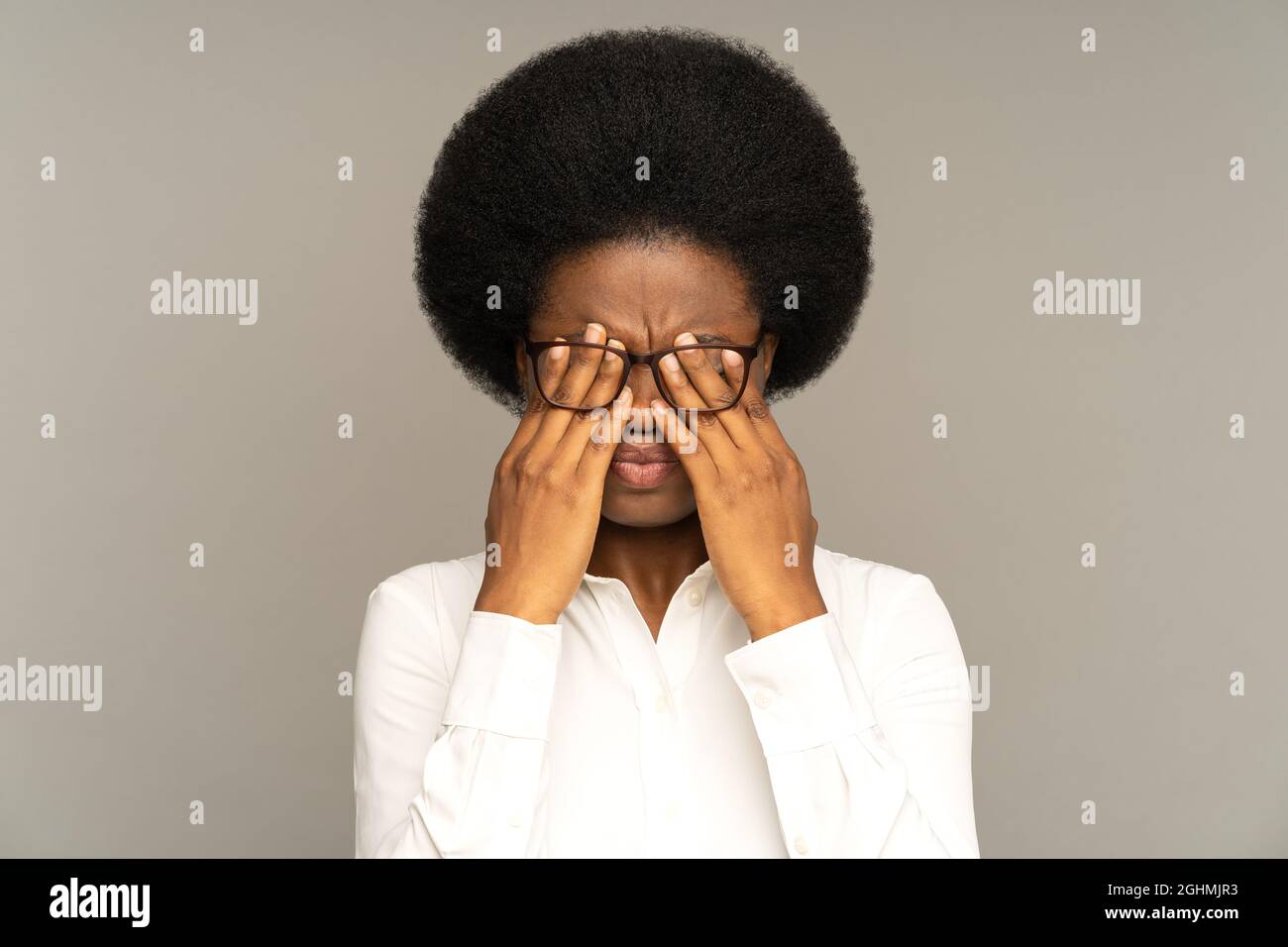 Erschöpftes afro Weibchen fühlt sich müde und reibt nach der Arbeit das Auge. Müdigkeit, Überlastung, Computer. Stockfoto
