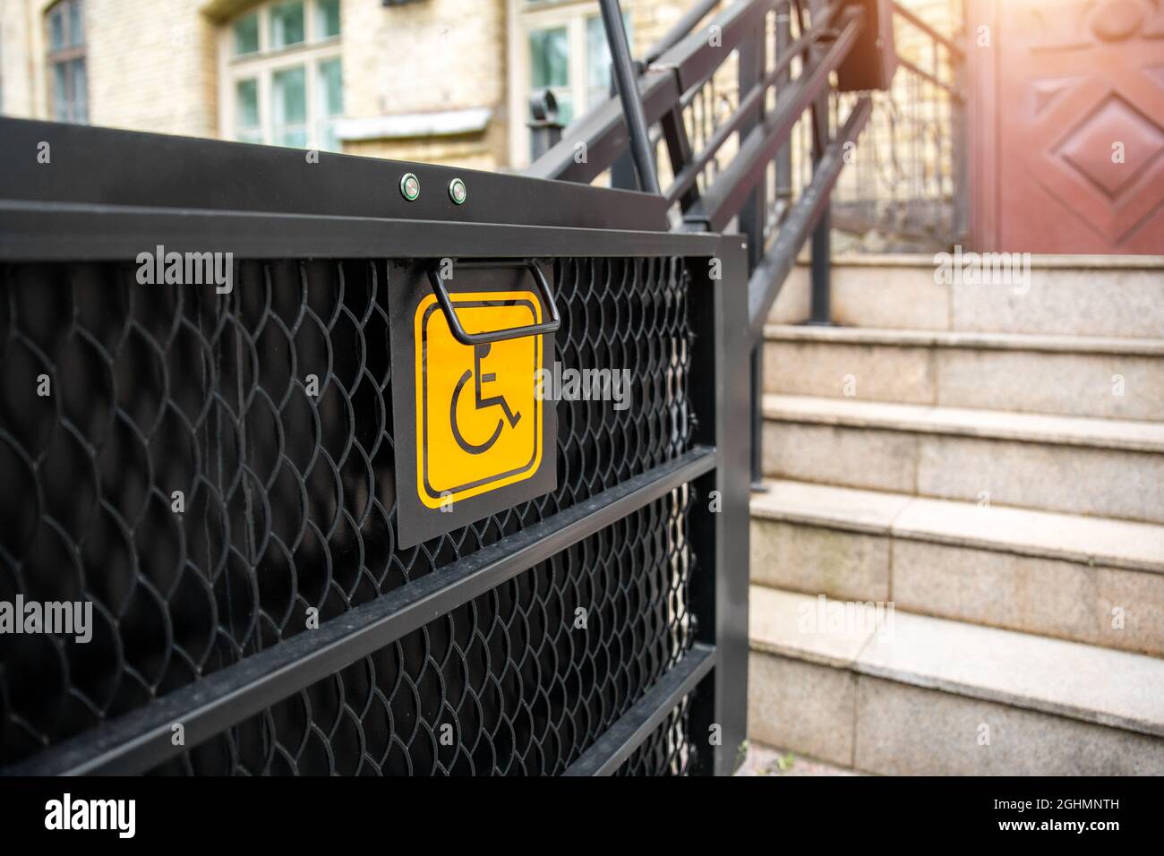 Elektrischer Plattformlift an der Gebäudetreppe für behinderte Menschen mit Rollstuhlschild an der alten Stadtstraße. Aufzug Treppenlift Rampe Mechanismus für Stockfoto