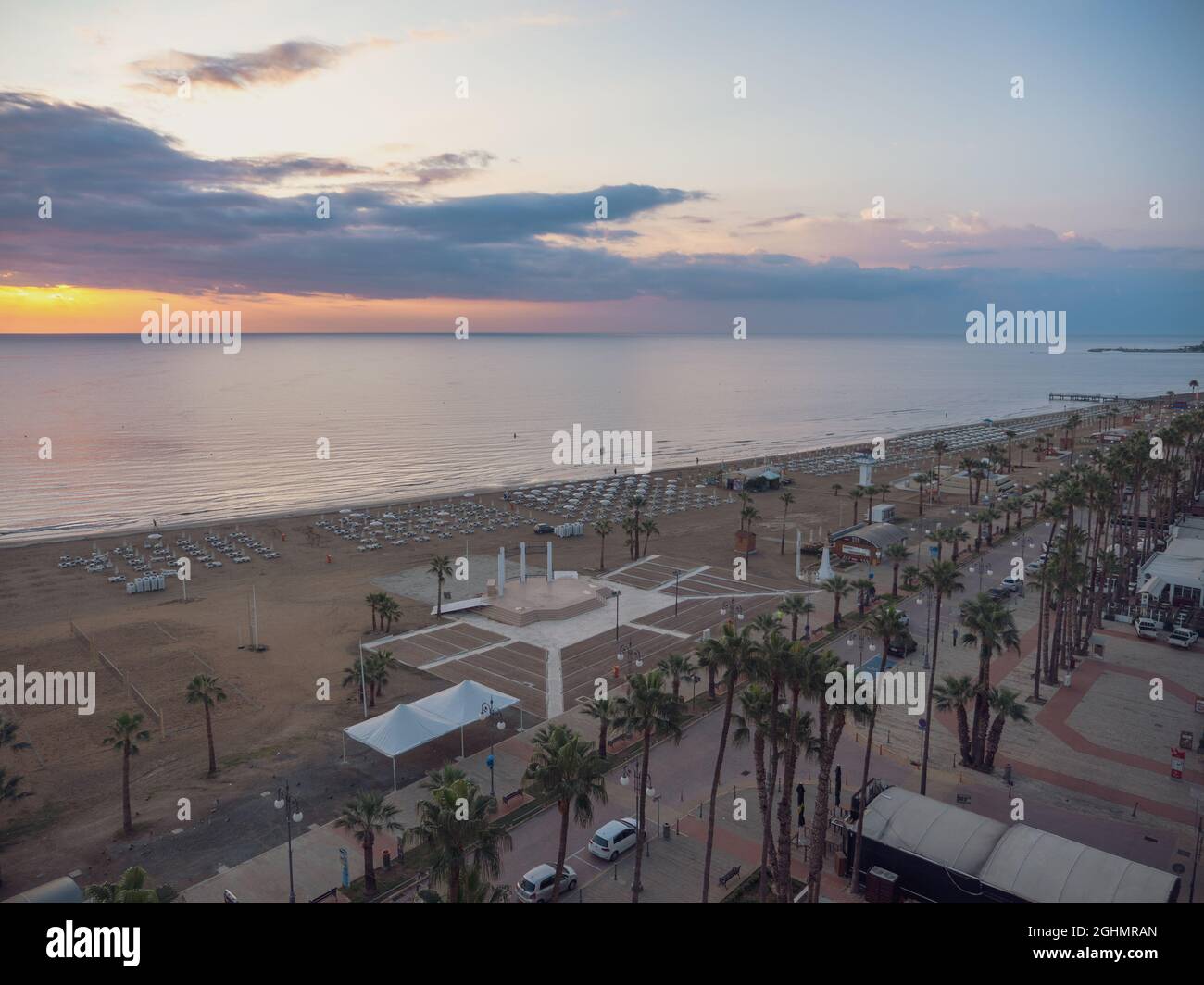Top Luftbild mit Blick auf Finikoudes Palmenpromenade, Volleyballplatz am Strand und Yachten am Mittelmeer in Larnaca Stadt, Zypern Stockfoto