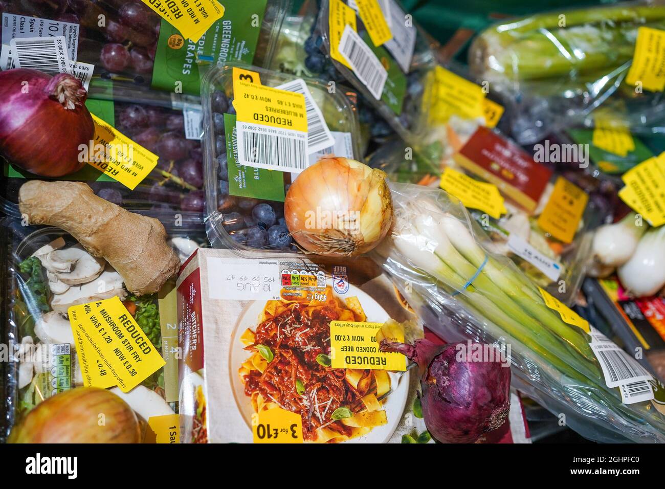 Lebensmittelprodukte im Supermarkt mit reduzierten gelben Aufklebern aufgrund der kurzen Haltbarkeit, veralbten Etiketten. Reduzierung und Vermeidung von Lebensmittelabfällen im Vereinigten Königreich. Stockfoto