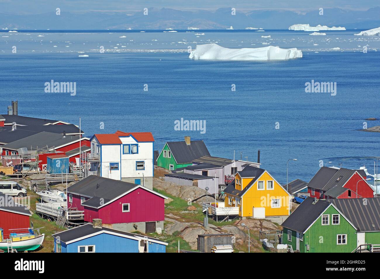 Häuser in verschiedenen Farben, Eisberge in einer Bucht vor der Insel, Arktis, Ilulissat, Disko Bay, Disko Island, Grönland, Dänemark Stockfoto