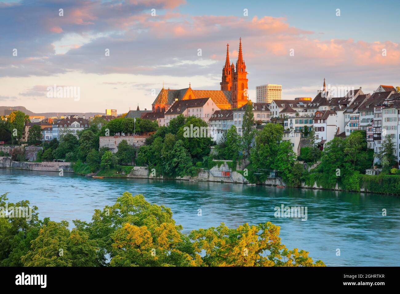 Blick auf den Basler Dom mitten in der Altstadt von Basel mit dem türkisfarbenen Rhein im Vordergrund Stockfoto