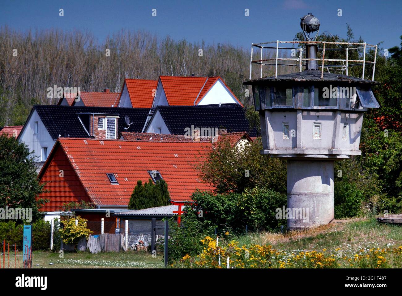Grenzbefestigung mit Säulengang, Lochplattenweg, Beobachtungsturm der DDR-Grenztruppen, Grenzwächter und Häuser von Stockfoto