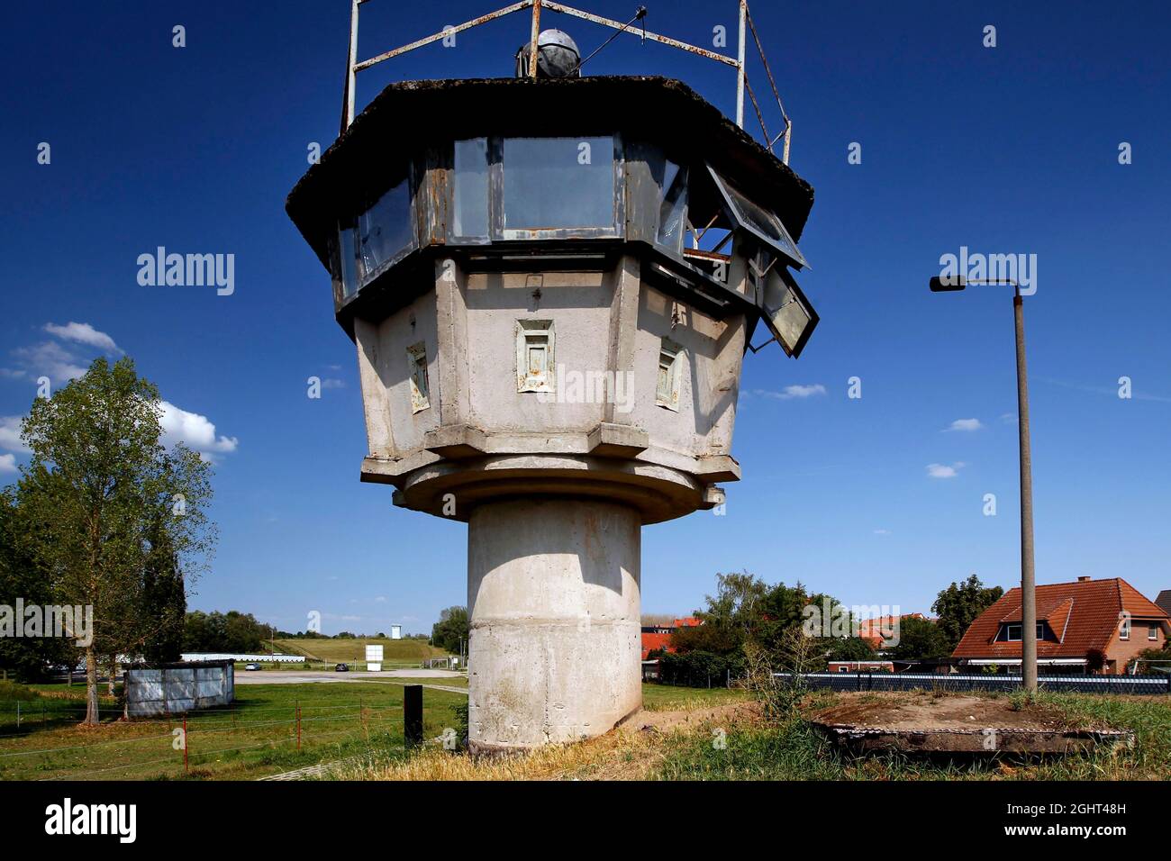 Grenzbefestigung mit Säulengang, Lochplattenweg, Beobachtungsturm der DDR-Grenztruppen, Grenzwächter und Häuser von Stockfoto