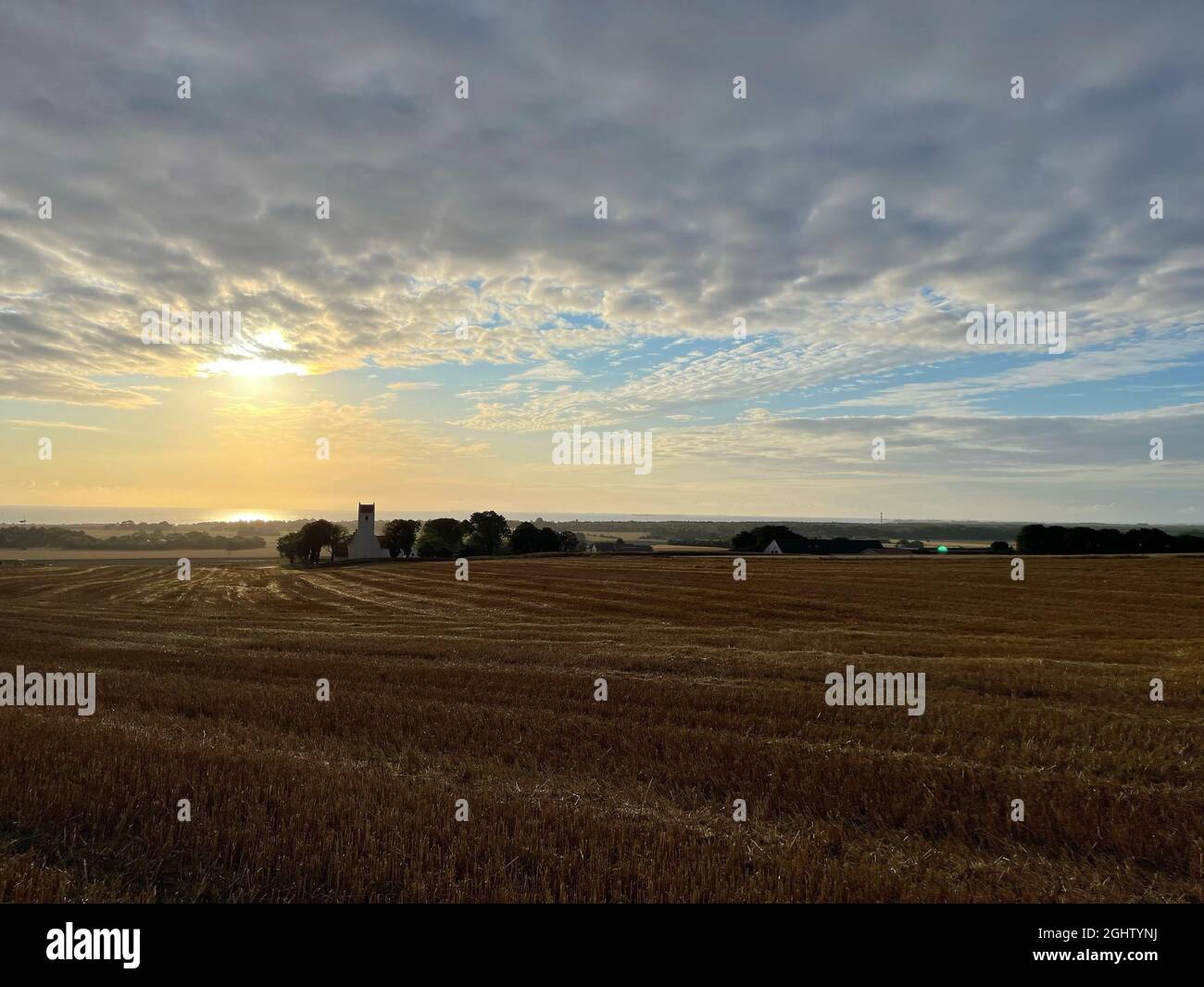 Ländliche Landschaft bei Sonnenaufgang mit Nordby Kirche und Küste in der Ferne, Samsoe, Jütland, Dänemark Stockfoto