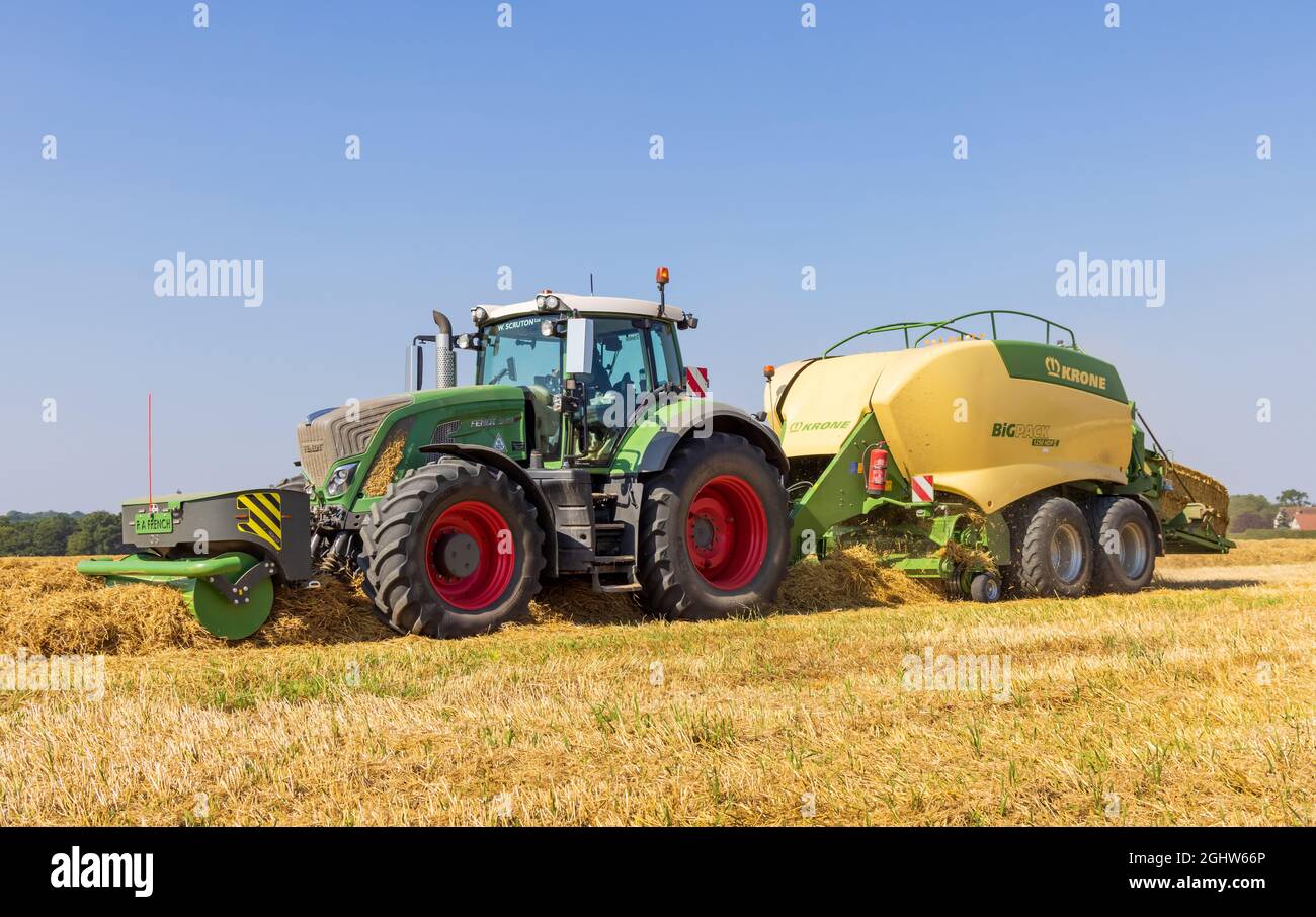 Traktor und Ballenpresse und Strohballenpresse auf einem Feld. Stockfoto