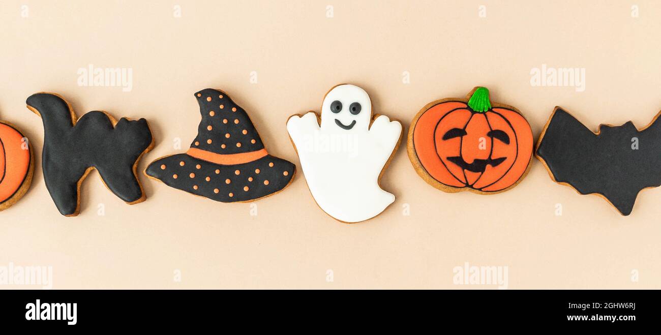 Verschiedene Halloween Lebkuchen - Jack O'Lanterns, Geister, Fledermaus und schwarzer Hut auf beigem Hintergrund. Halloween-Konzept. Draufsicht. Banner Stockfoto