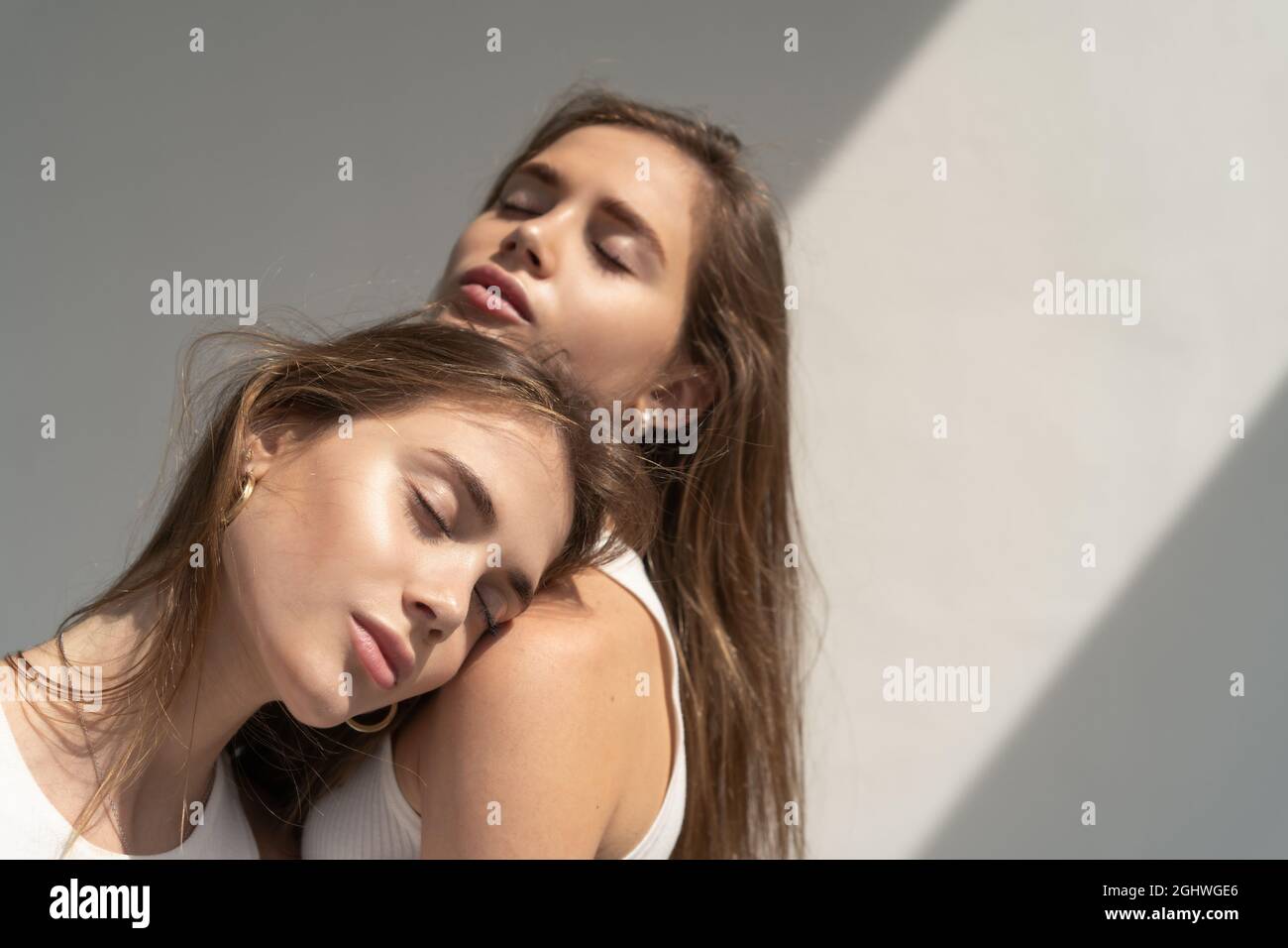 Portrait von Zwillingsschwestern, die im Sonnenlicht stehen Stockfoto