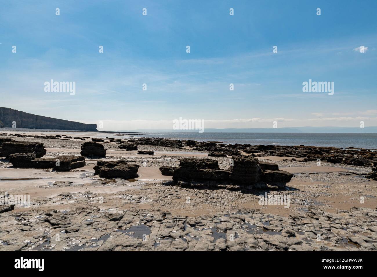 Eine Küstenlandschaft mit riesigen Felsplatten am walisischen Strand, der sich auf die ikonische Klippe am nash Point zurückgeht Stockfoto