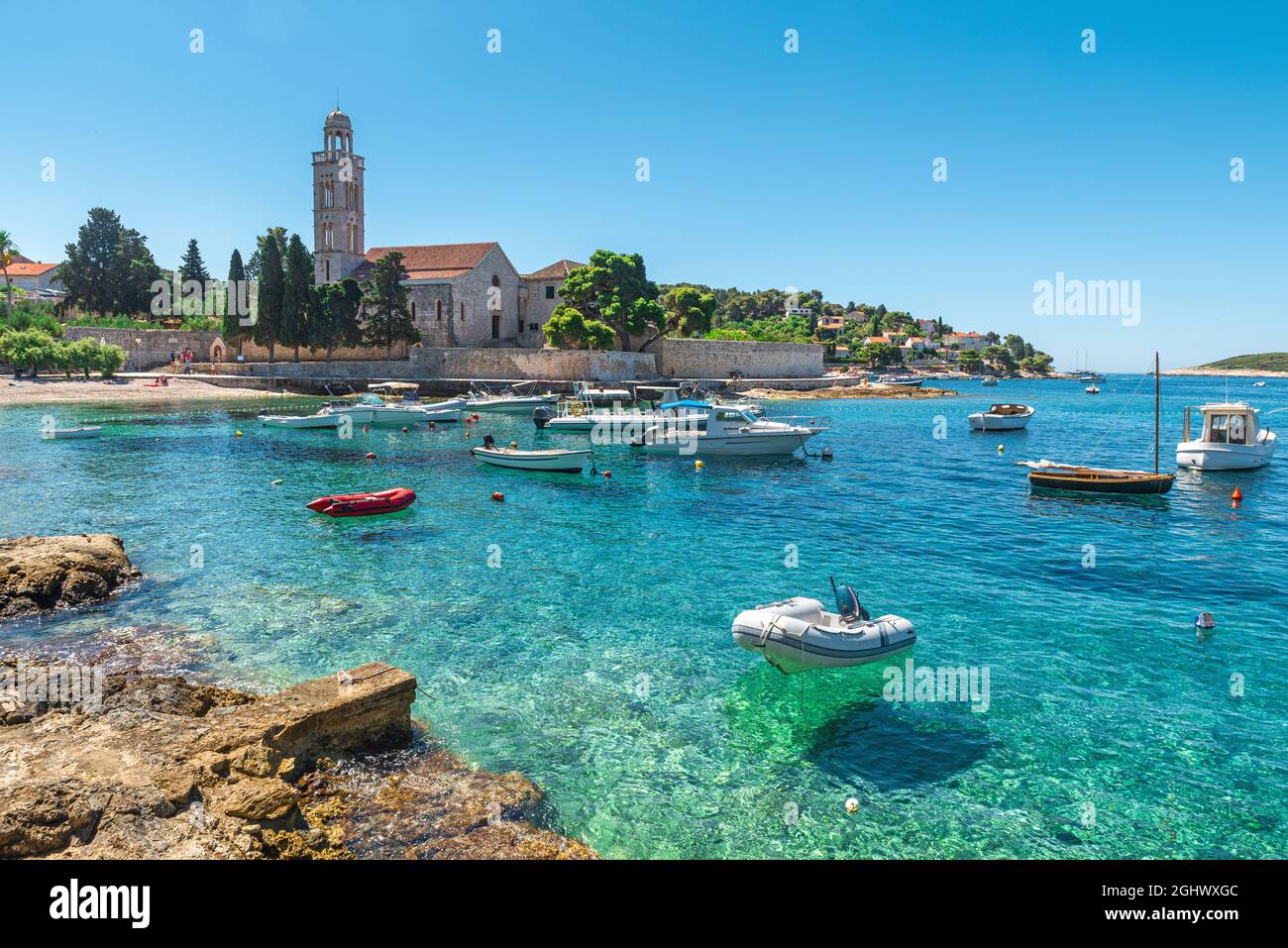 Türkisfarbenes Wasser der Adriatischen Meeresbucht auf der Insel Hvar mit franziskanerkloster und Booten in Dalmatien, Kroatien. Urlaubsziel im Sommer Stockfoto