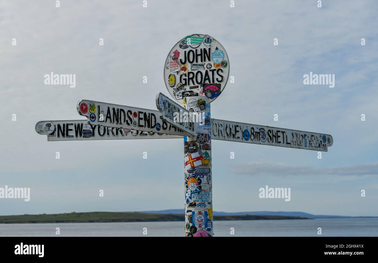 Mehrere Ziel- und Entfernungsschilder mit Aufklebern, John O'Groats, Caithness, Schottland, Großbritannien Stockfoto