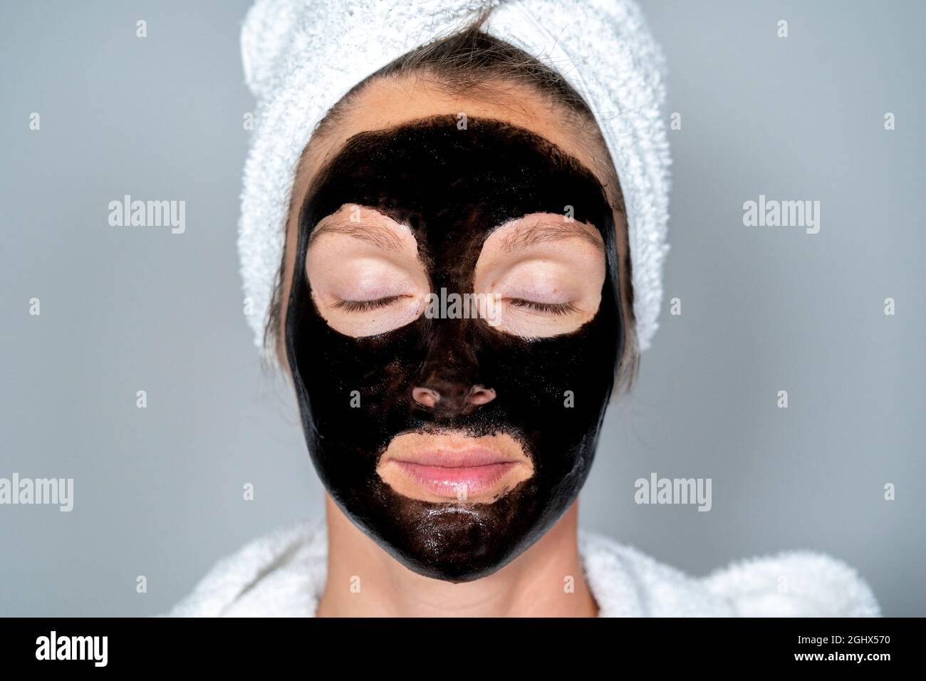 Junge Frau zu Hause Spa mit schwarzer Gesichtsmaske. Wellness-Konzept Gesichtsbehandlung Stockfoto