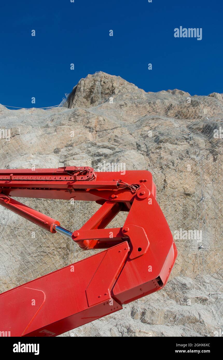 Arbeitet auf einer Straße, Maschinen und Bauelemente, Schutzgitter aus Metall, um das Einstürzen von Steinen und Steinen auf einer Straße zu verhindern Stockfoto