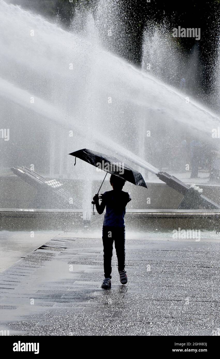Ein Kind tanzt unter den Springbrunnen in Paris, Frankreich. Stockfoto