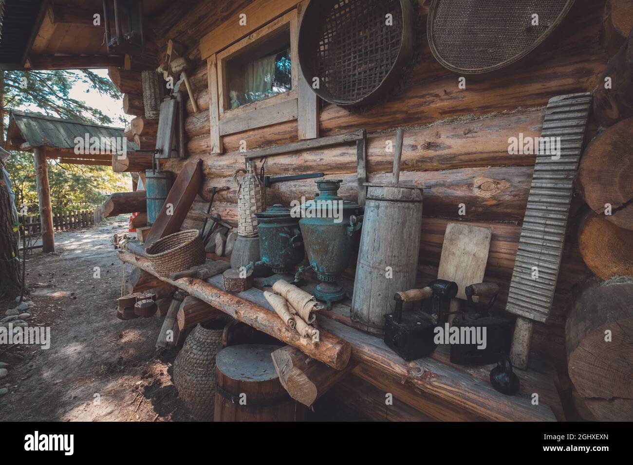 Retro-Haushaltswaren auf einer Holzbank in der Nähe der Holzwand. Antike Haushaltsgegenstände von Bauern. Stockfoto