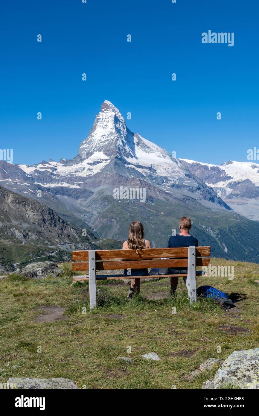 Ein paar Touristen saßen auf einer Holzbank und beobachteten Matterhorn, Zermatt, Wallis, Schweiz Stockfoto