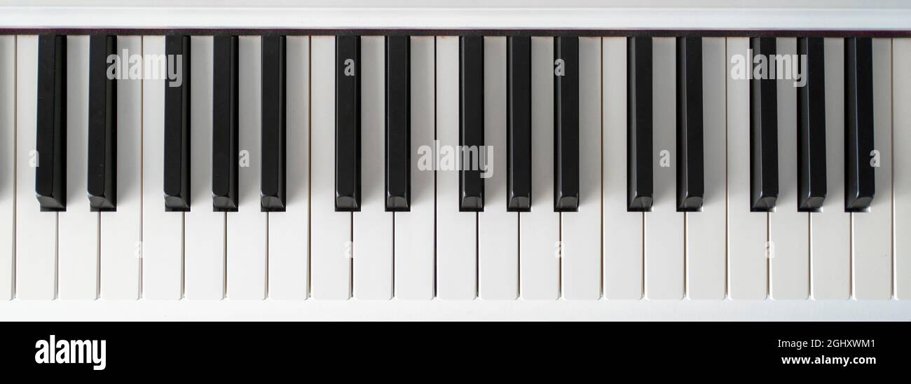 Klaviertastatur. Klassische Musik auf elektronischem Digitalpiano. Blick von der flachen Oberseite auf Holzboden. Wunderschöne weiße Klaviertasten. Stockfoto
