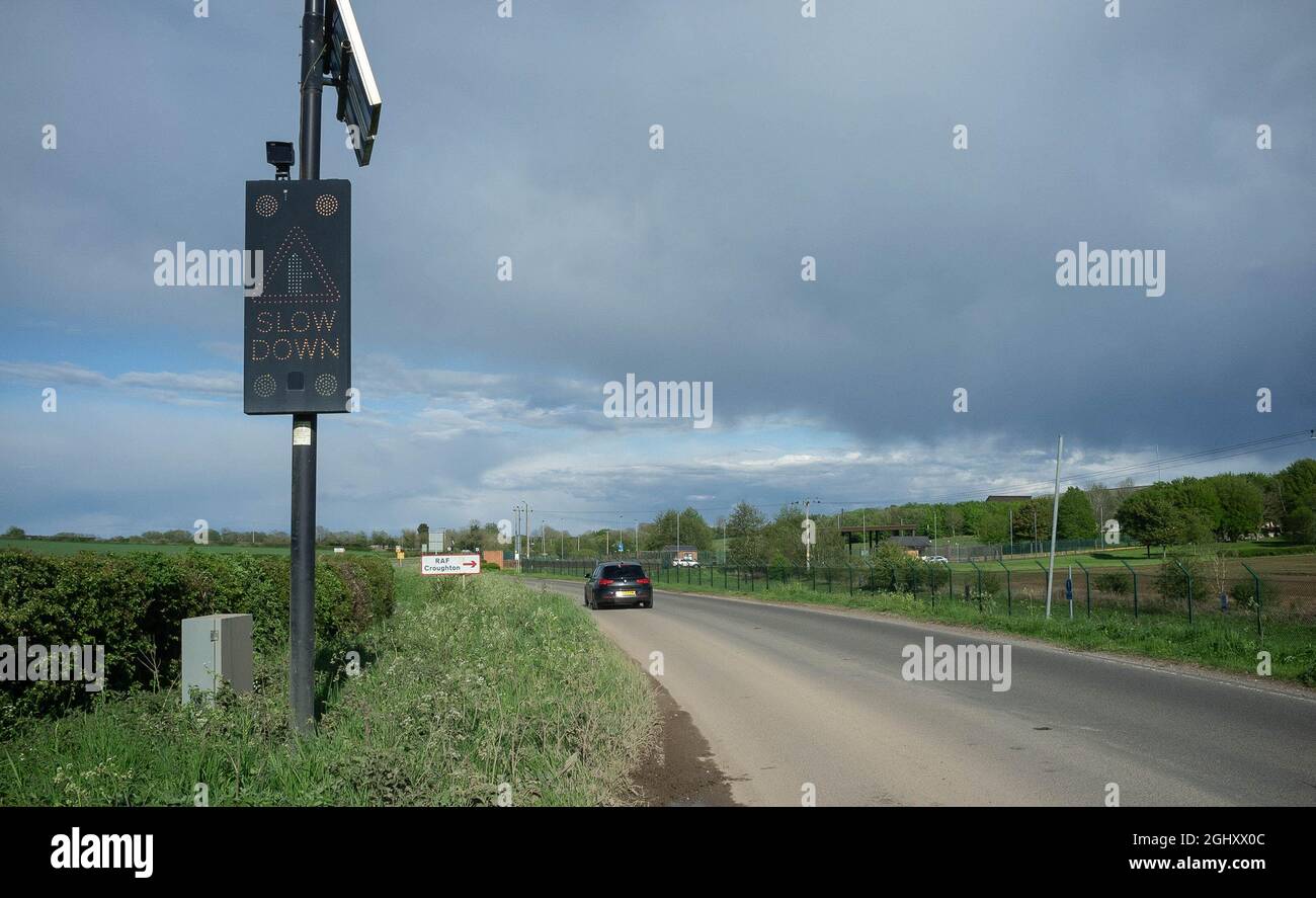 Ein solarbetriebenes LED-Warnschild auf der B4031 außerhalb von RAF Croughton, Northamptonshire, „verlangsamt“. Stockfoto