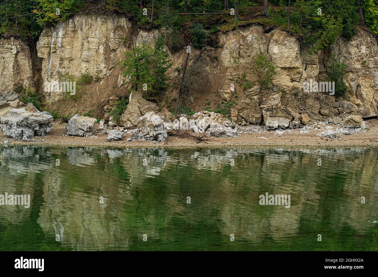 Bewaldete Flussufer mit zerbröckelnden Marmorklippen, Wassererosion von Küstenfelsen Stockfoto