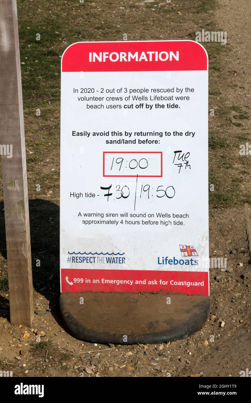 Ein RNLI-Schild am Holkham Beach in North Norfolk warnt vor den Gefahren, die durch die Flut abgetrennt werden. Stockfoto